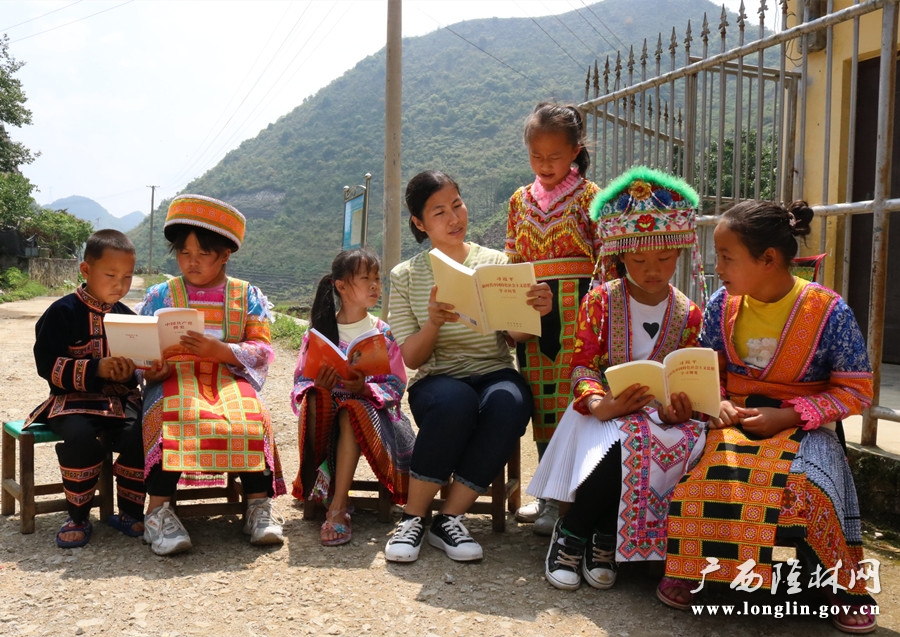 图为该镇文化站工作人员指导苗寨孩子进行文段朗读