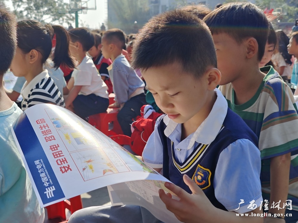同学们拿到安全用电知识宣传单后认真阅读安全用电知识内容。王亚玲  摄