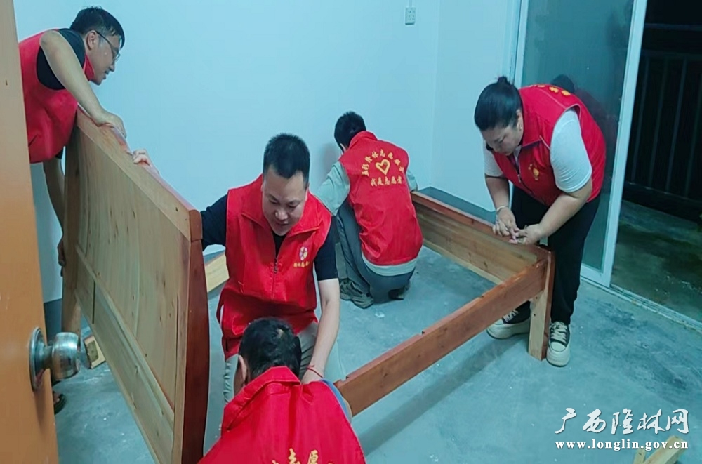志愿者合力组装木质床架。罗林杰 摄
