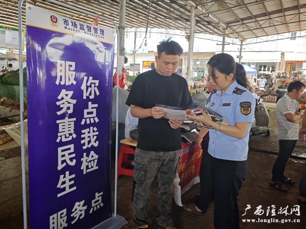 图为自治县市场监管局工作人员向现场群众解答